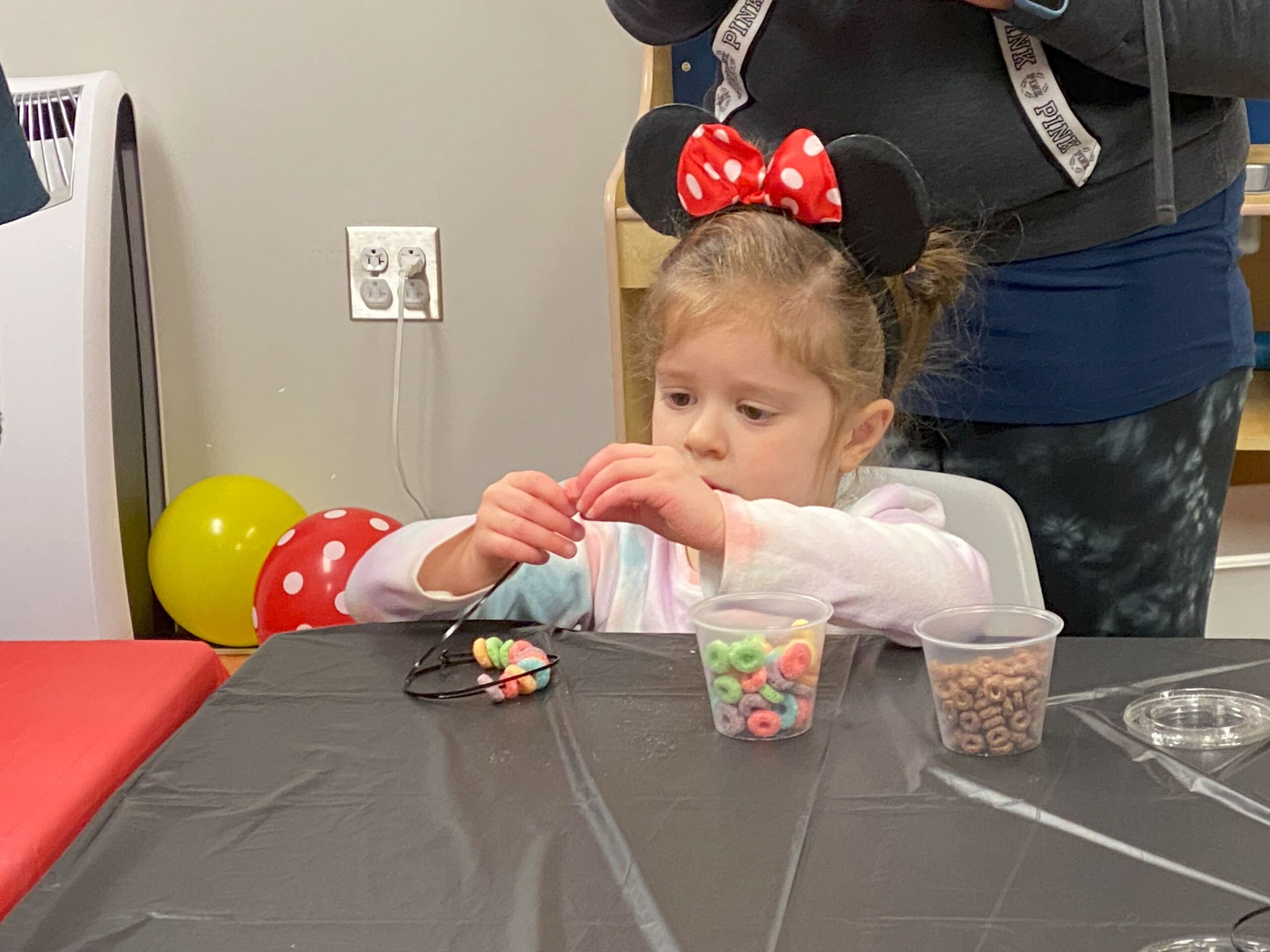 Young girl in Minnie Mouse ears making crafts