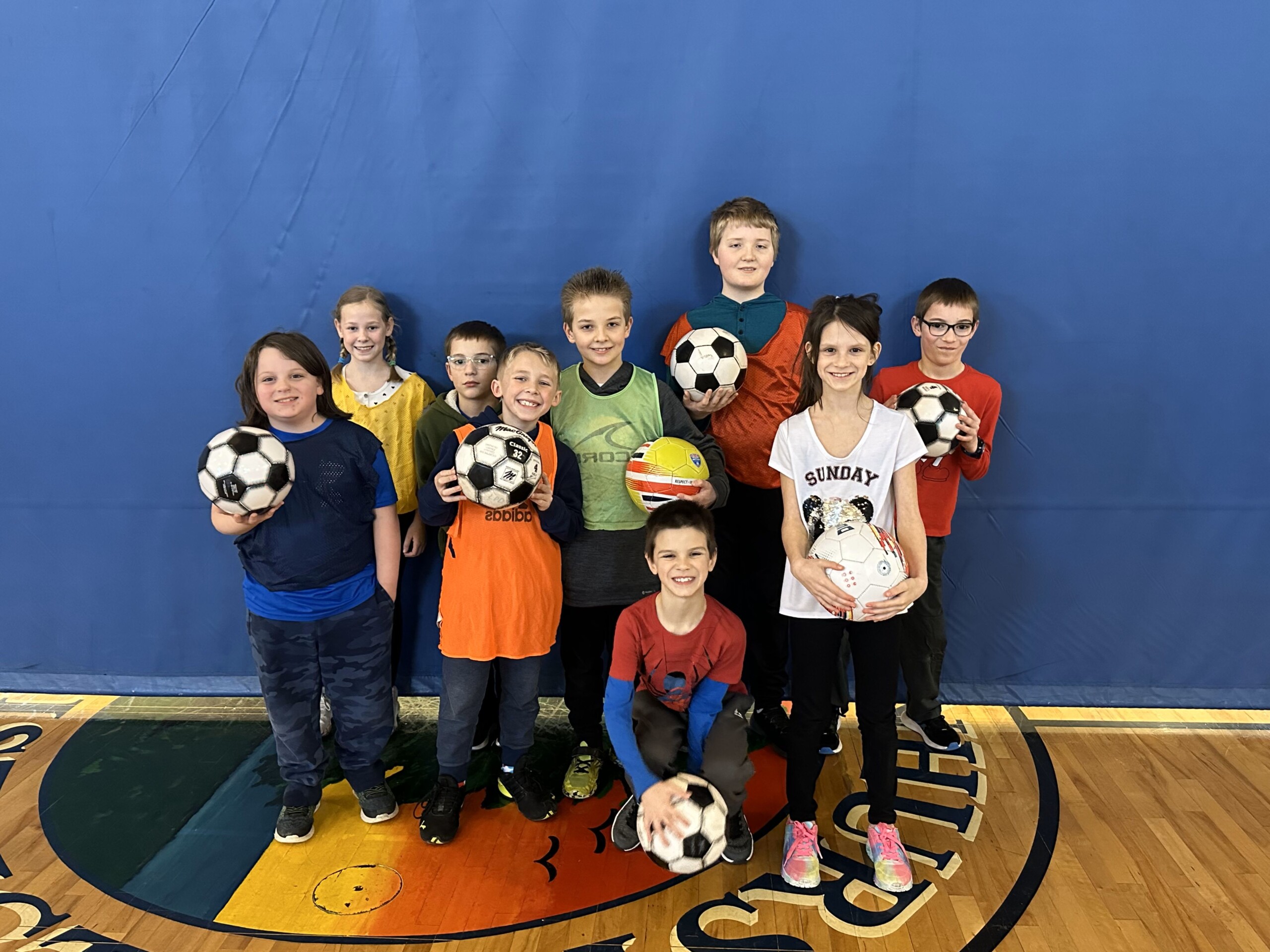 Group photo of young kids posing with soccer balls